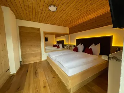 a bedroom with a large bed with a wooden ceiling at Stroblhof in Vipiteno