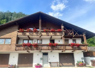 a building with red flowers on the balconies at Stroblhof in Vipiteno