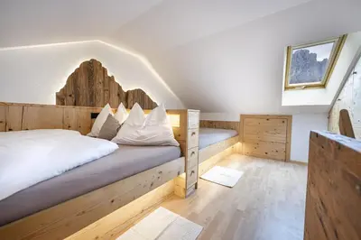 a bedroom with a bed with a wooden headboard at Apartments Rondula Pic in Santa Cristina in Val Gardena