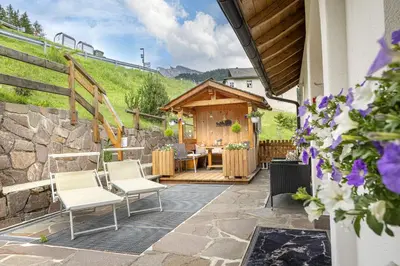 a patio with chairs and a wooden building at Apartments Rondula Pic in Santa Cristina in Val Gardena