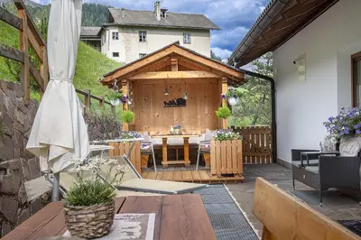 an outdoor patio with a table and a wooden building at Apartments Rondula Pic in Santa Cristina in Val Gardena