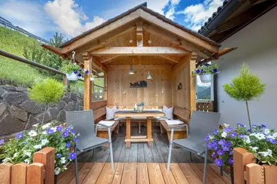 a wooden deck with a wooden table and chairs at Apartments Rondula Pic in Santa Cristina in Val Gardena
