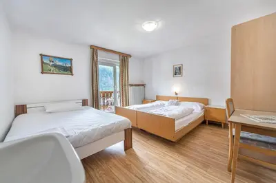 a bedroom with two beds and a desk and a window at Apartments Martina in Selva