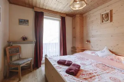 a bedroom with a bed and a chair and a window at Apartments Martina in Selva