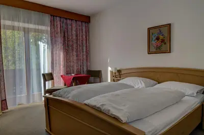 a bedroom with a bed and a window with a table at Garni Kofler in Tirolo