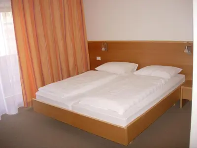 a large bed with white sheets and pillows at Garni Kofler in Tirolo