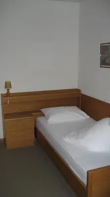 a bedroom with two beds and a wooden headboard at Garni Kofler in Tirolo