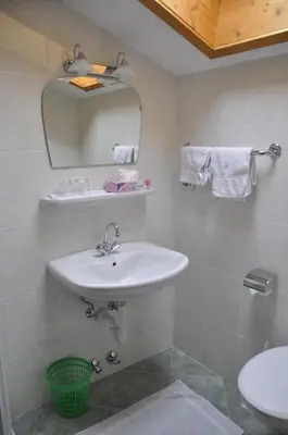 a white bathroom with a sink and a mirror at Garni Kofler in Tirolo