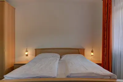 a bed with white sheets and two pillows on it at Garni Kofler in Tirolo