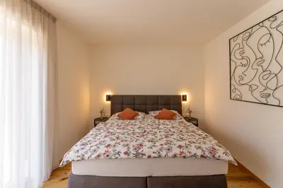 a bedroom with a large bed with a floral bedspread at Apartments Villa Julia in Lana