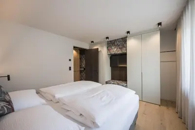 a white bedroom with two beds and a closet at Luis Chalet in Brunico
