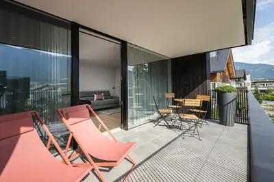 a patio with chairs and tables on a balcony at Luis Chalet in Brunico