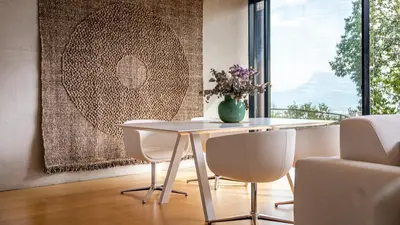 a table with white chairs and a vase of flowers on it at Olivia in Tirolo