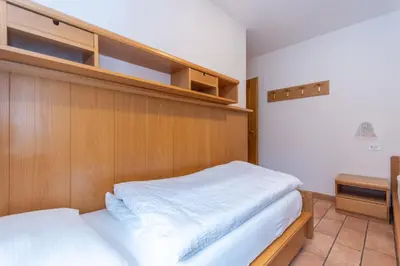 a bedroom with a bed with a wooden headboard at Appartamento Monzoni in Pozza di Fassa