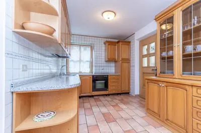 a kitchen with wooden cabinets and a tile floor at Appartamento Monzoni in Pozza di Fassa