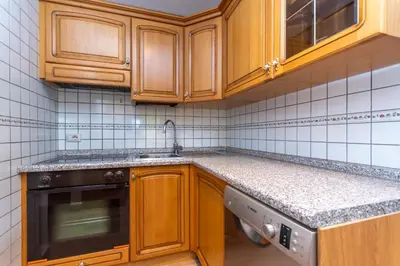 a kitchen with wooden cabinets and granite counter tops at Appartamento Vajolet in Pozza di Fassa