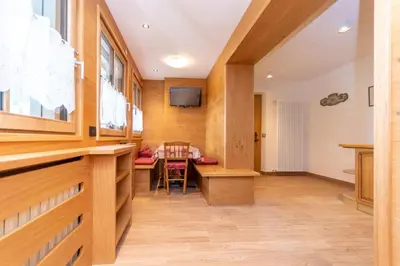 a room with a table and chairs and a television at Appartamento Vajolet in Pozza di Fassa