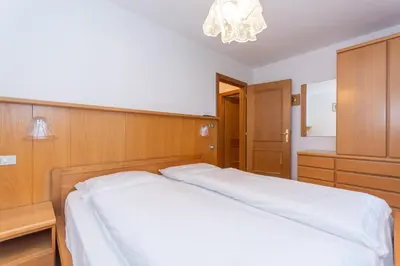 a bedroom with a bed and a chandelier at Appartamento Vajolet in Pozza di Fassa