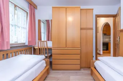 a bedroom with two beds and a cabinet at Appartamento Vajolet in Pozza di Fassa