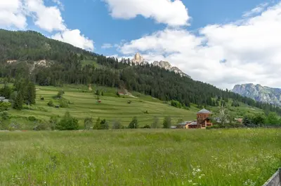 a green field with a gazebo in the mountains at Appartamento Vajolet in Pozza di Fassa