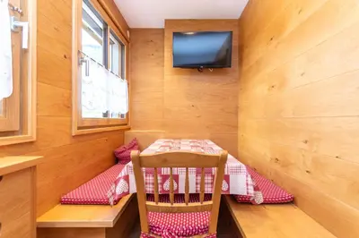 a small dining room with a table and a tv at Appartamento Vajolet in Pozza di Fassa
