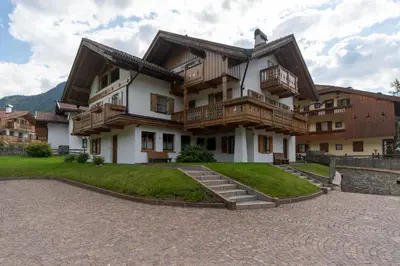 a large apartment building with wooden balconies and stairs at Appartamento Vajolet in Pozza di Fassa