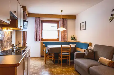 a kitchen and living room with a table and a couch at Apartment Suliva in Santa Cristina in Val Gardena