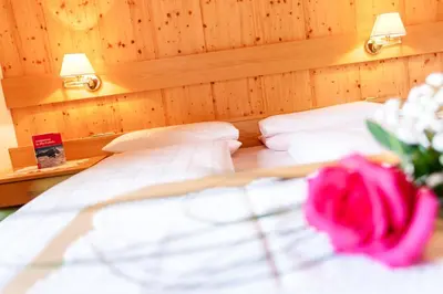 a bedroom with two beds and a pink rose at Gasthof Tuscherhof in Braies
