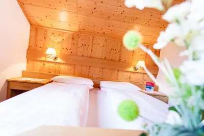 two beds in a room with a wooden headboard at Gasthof Tuscherhof in Braies