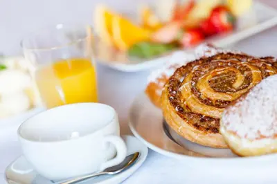 a table with a plate of pastries and a cup of orange juice at Gasthof Tuscherhof in Braies