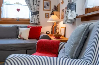 a living room with a couch and a red chair at Cesa Leo in Canazei
