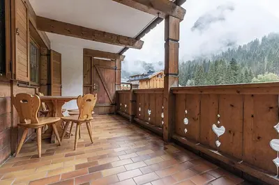 a porch with a table and chairs on a balcony at Cesa Testa in Canazei