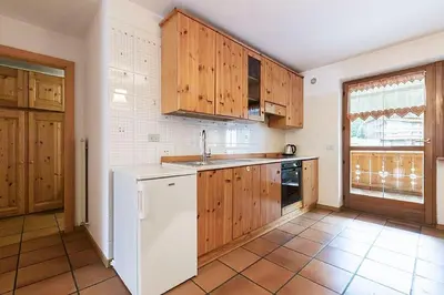 a kitchen with wooden cabinets and a white refrigerator at Cesa Testa in Canazei