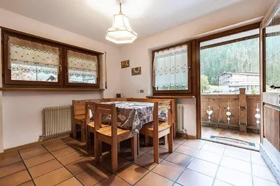 a dining room with a table and some windows at Cesa Testa in Canazei