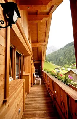 a porch of a wooden house with a bench on it at Ciasa Mirio' in La Valle