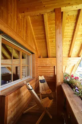 a rocking chair on the porch of a log cabin at Ciasa Mirio' in La Valle