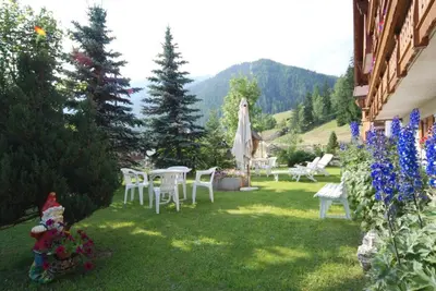 a garden with tables and chairs in the grass at Appartamenti Césa Col De Pin in Canazei