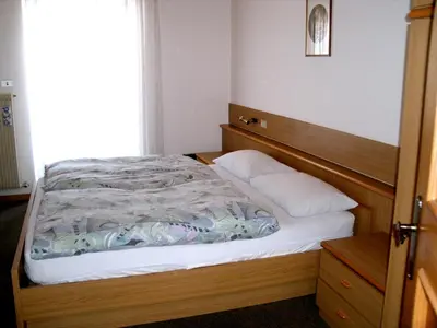 a bedroom with a bed with a wooden headboard at Appartamenti Césa Col De Pin in Canazei