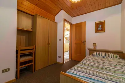 a bedroom with a bed and a wooden ceiling at Appartamenti Césa Col De Pin in Canazei