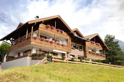 a building on a hill with flowers on it at Apartman Anda in Cavalese