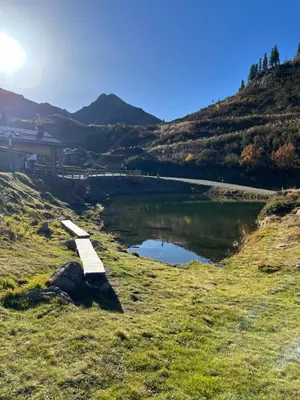 a bench on a hill next to a lake at Apartman Anda in Cavalese