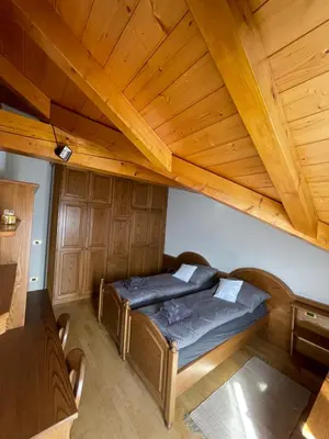 a bed in a room with a wooden ceiling at Apartman Anda in Cavalese