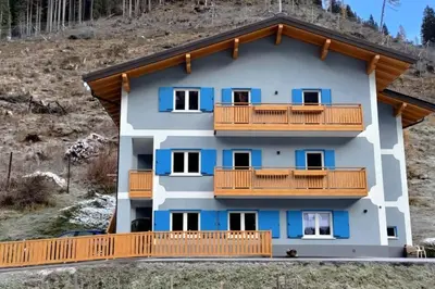 a building with a balcony with blue at Ciamorc Relax & Sport Appartament for max 2 Adults 1 child 1 infant in Canazei