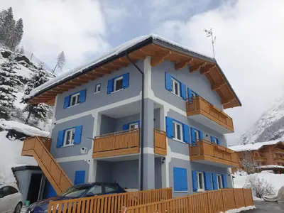 a blue building with wooden balconies in the snow at Ciamorc Relax & Sport Appartament for max 2 Adults 1 child 1 infant in Canazei
