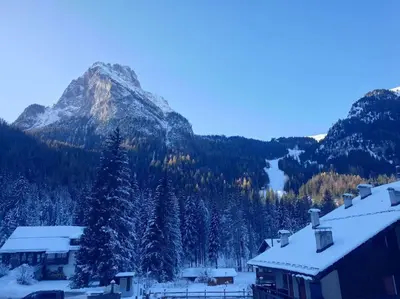 a snow covered mountain with a house and trees at Ciamorc Relax & Sport Appartament for max 2 Adults 1 child 1 infant in Canazei