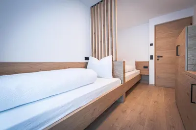 a bedroom with a large white bed and wooden floors at MANARES - my mountain stay in San Lorenzo di Sebato
