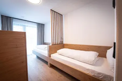 a bedroom with two beds and a large window at MANARES - my mountain stay in San Lorenzo di Sebato