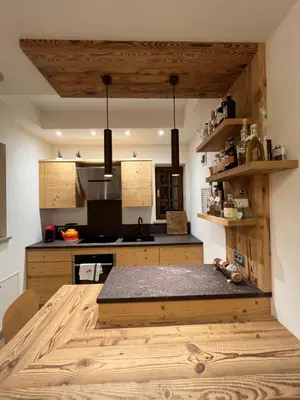 a kitchen with wooden cabinets and a wooden floor at Casalta by Go New Location in Moena