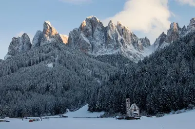 a snow covered mountain range with a house in the foreground at Waldheim Appartements in Bressanone