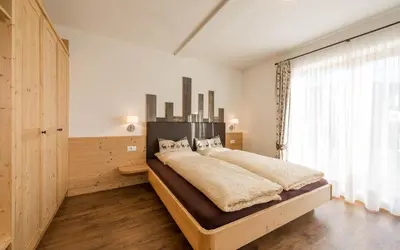 a bedroom with a large bed and a large window at Waldheim Appartements in Bressanone